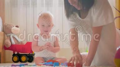 妈妈和她的孩子在室内玩玩具。 在家里在地板上爬行有趣的小男孩。 妈妈和小儿子一起玩
